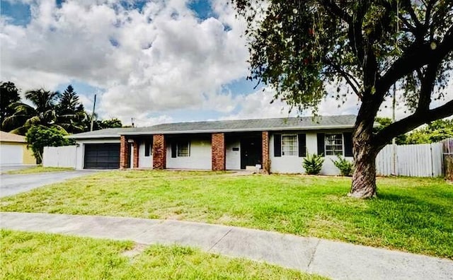 single story home with aphalt driveway, an attached garage, brick siding, fence, and a front lawn