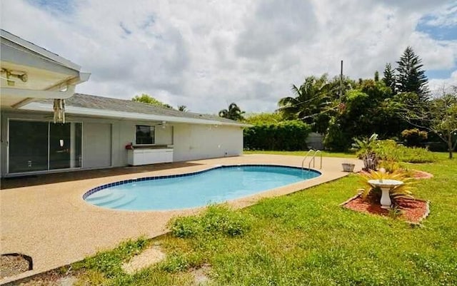 pool featuring a patio and a lawn