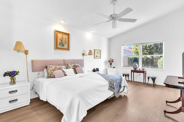 bedroom with a ceiling fan, vaulted ceiling, and wood finished floors