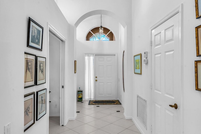 foyer featuring a notable chandelier, lofted ceiling, visible vents, light tile patterned flooring, and baseboards