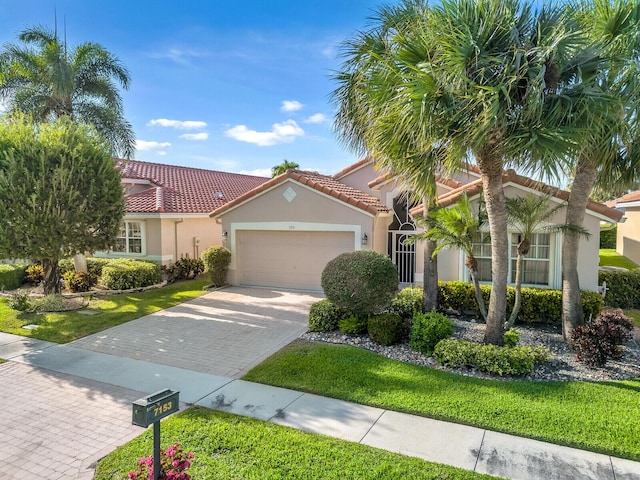 mediterranean / spanish home with a garage, stucco siding, a tile roof, decorative driveway, and a front yard