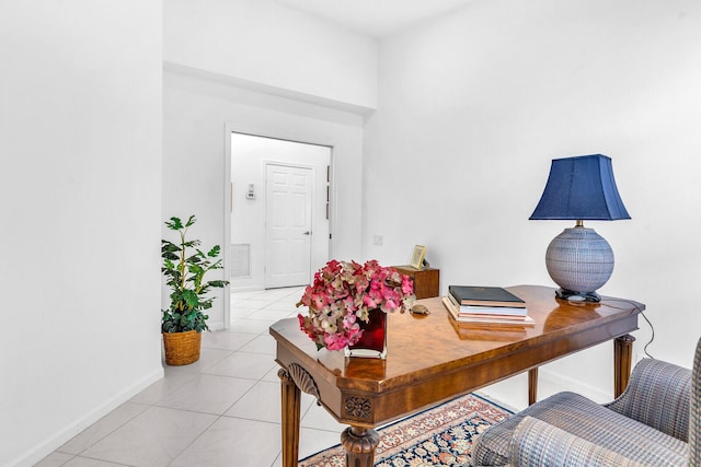 office area featuring a high ceiling, light tile patterned flooring, and baseboards