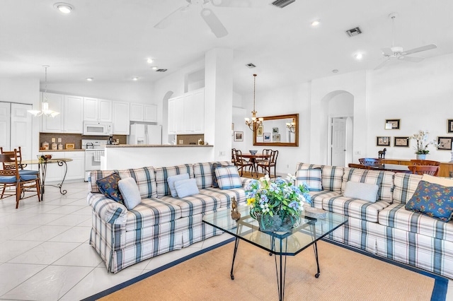 living room featuring high vaulted ceiling, arched walkways, light tile patterned flooring, and ceiling fan with notable chandelier