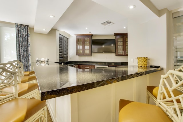 kitchen featuring visible vents, recessed lighting, dark stone counters, and glass insert cabinets