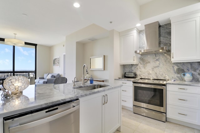 kitchen with tasteful backsplash, stainless steel appliances, white cabinetry, wall chimney exhaust hood, and a sink