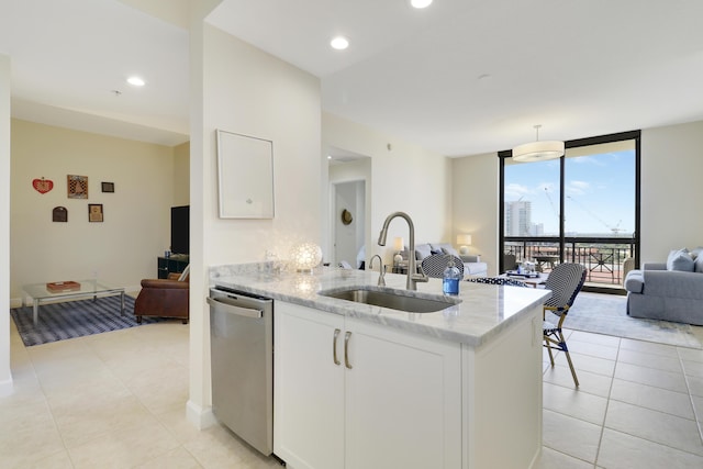 kitchen with a sink, expansive windows, light stone counters, stainless steel dishwasher, and open floor plan