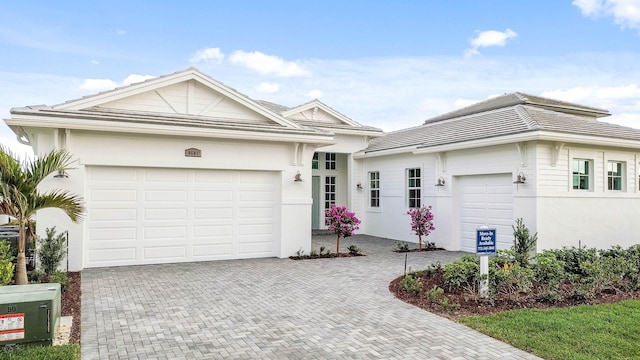 single story home featuring decorative driveway, an attached garage, and stucco siding