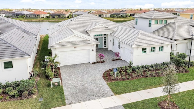 view of front facade with a residential view, decorative driveway, an attached garage, and stucco siding