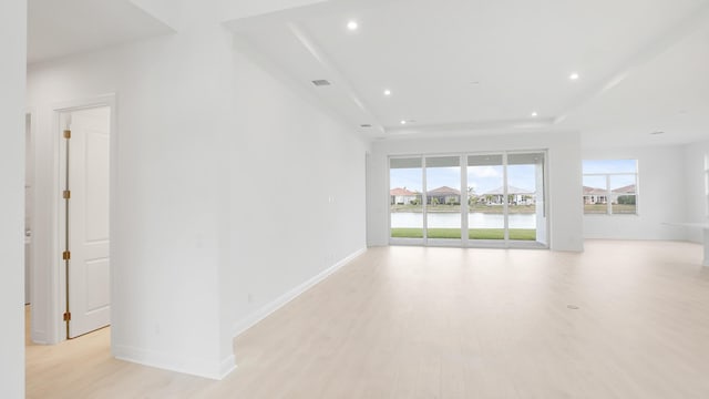 spare room featuring a tray ceiling, recessed lighting, visible vents, light wood-style floors, and baseboards