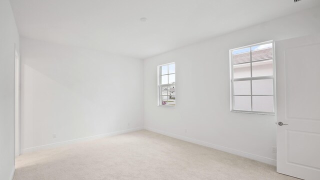 unfurnished room featuring light carpet and baseboards