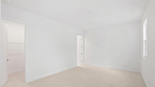 empty room featuring light carpet and baseboards