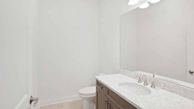 bathroom with wood finished floors, vanity, toilet, and baseboards