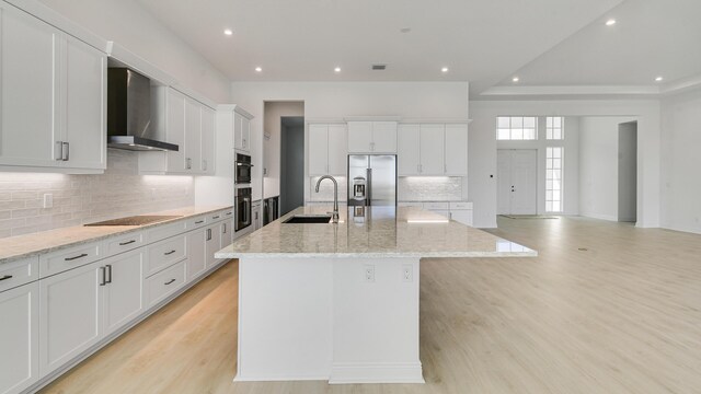 kitchen with stainless steel appliances, visible vents, light wood-style floors, white cabinets, and wall chimney exhaust hood