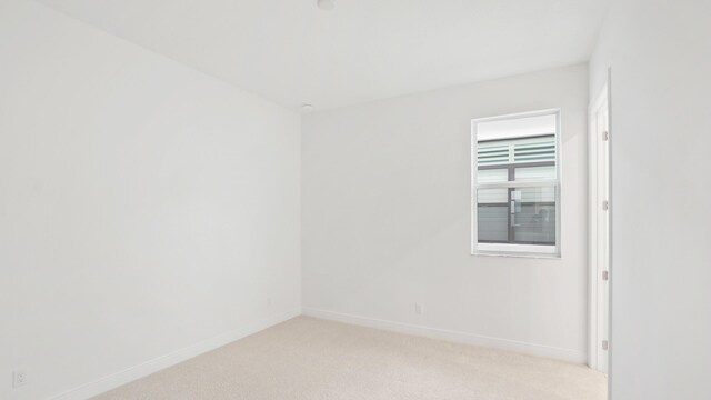 empty room featuring baseboards and light colored carpet