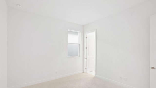 unfurnished room featuring light carpet and baseboards