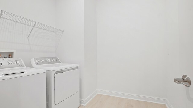 laundry area with washer and dryer, laundry area, light wood finished floors, and baseboards