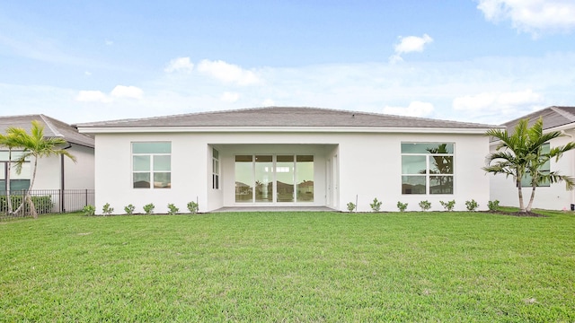 back of property with a lawn, fence, and stucco siding