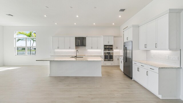 kitchen with visible vents, light wood-style flooring, appliances with stainless steel finishes, a tray ceiling, and a sink