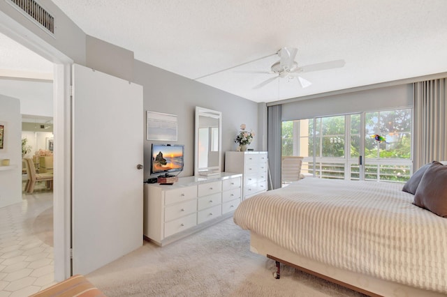 bedroom featuring a ceiling fan, visible vents, a textured ceiling, and light carpet