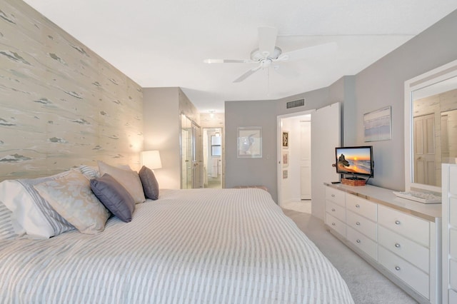 bedroom featuring light colored carpet, visible vents, a ceiling fan, connected bathroom, and wallpapered walls