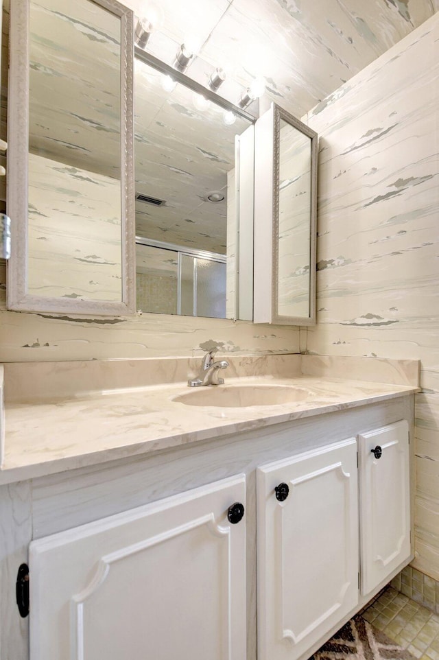 bathroom with wood walls, a shower stall, and vanity