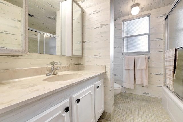 full bathroom featuring a shower with door, vanity, toilet, and tile patterned floors