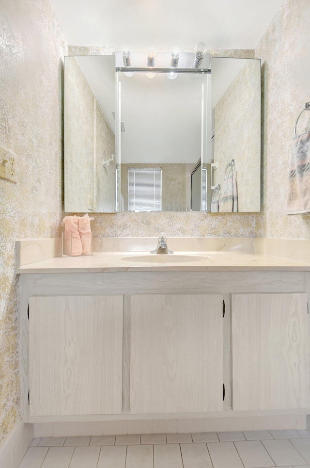 bathroom with tile patterned floors, vanity, and wallpapered walls