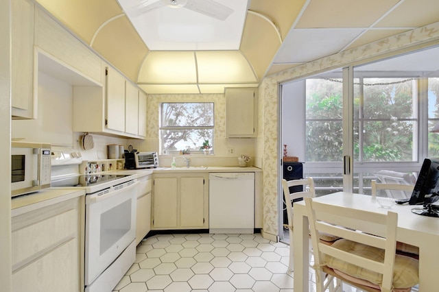 kitchen featuring white appliances, a toaster, light countertops, cream cabinetry, and a sink