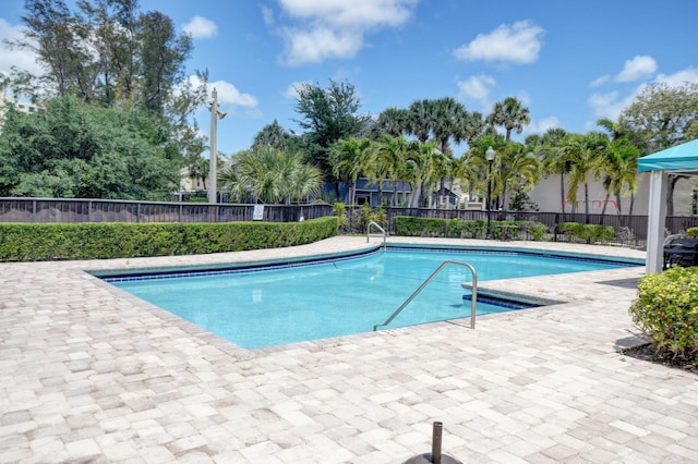 community pool with a patio and fence