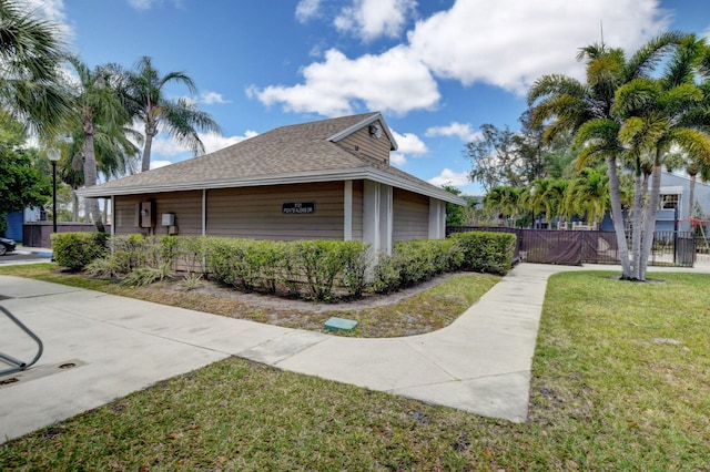 view of side of home featuring a yard, a shingled roof, and fence