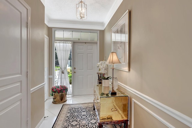 entrance foyer featuring a textured ceiling, ornamental molding, and light tile patterned flooring