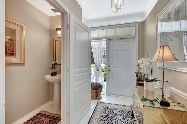 foyer featuring light tile patterned floors, a textured ceiling, visible vents, baseboards, and crown molding