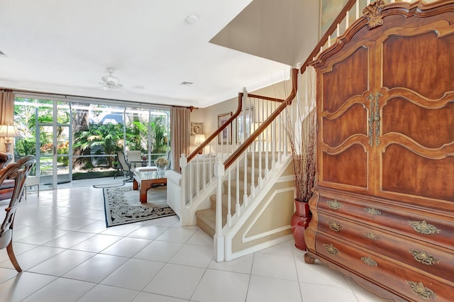 stairway with a ceiling fan and tile patterned floors