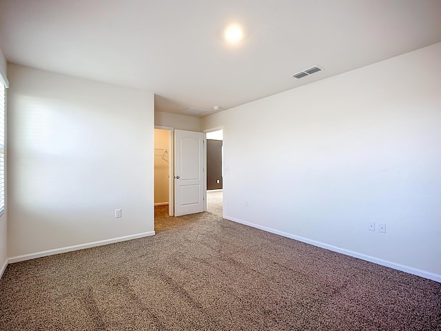 carpeted spare room featuring visible vents and baseboards