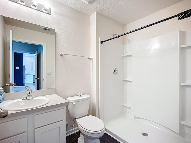 bathroom with a textured ceiling, a stall shower, vanity, and toilet