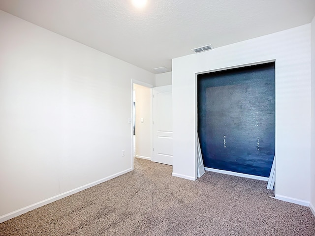 unfurnished bedroom with visible vents, baseboards, a textured ceiling, and carpet flooring