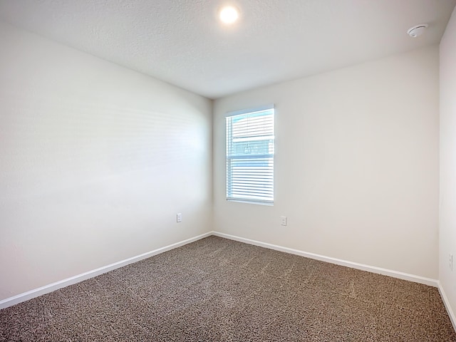 unfurnished room featuring carpet flooring, baseboards, and a textured ceiling