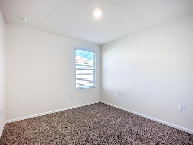 spare room featuring baseboards and carpet