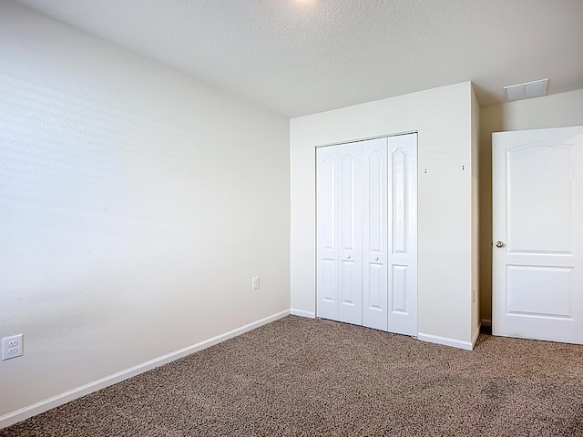 unfurnished bedroom with a closet, baseboards, carpet, and a textured ceiling