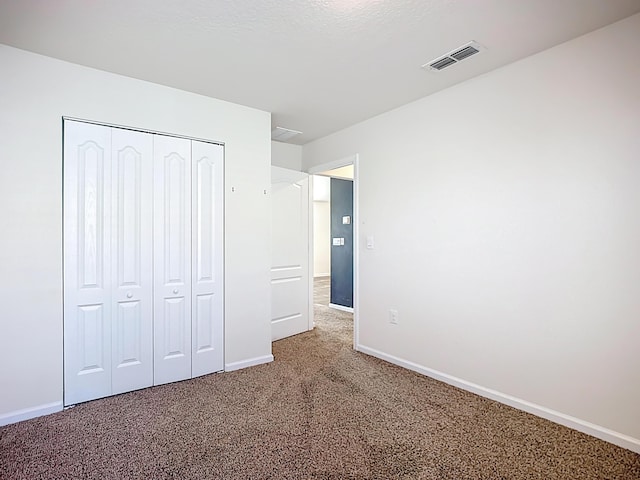 unfurnished bedroom featuring carpet, visible vents, a closet, and baseboards