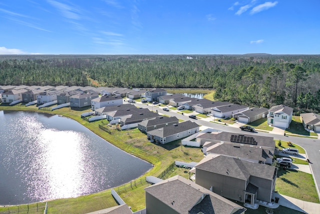 drone / aerial view with a residential view, a forest view, and a water view