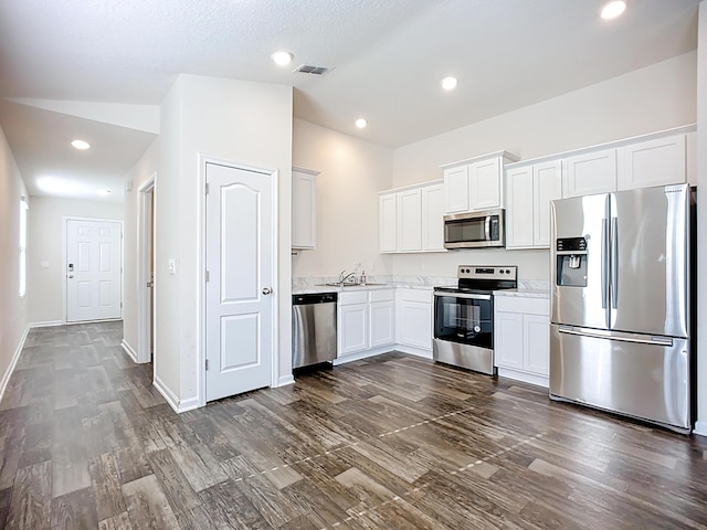 kitchen with lofted ceiling, recessed lighting, stainless steel appliances, dark wood-type flooring, and white cabinets