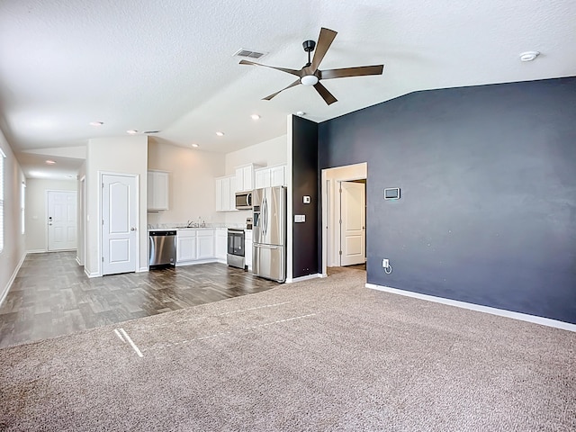 unfurnished living room with visible vents, baseboards, carpet, lofted ceiling, and a textured ceiling