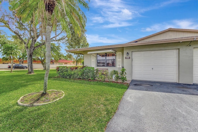 single story home featuring a garage, a front yard, driveway, and stucco siding