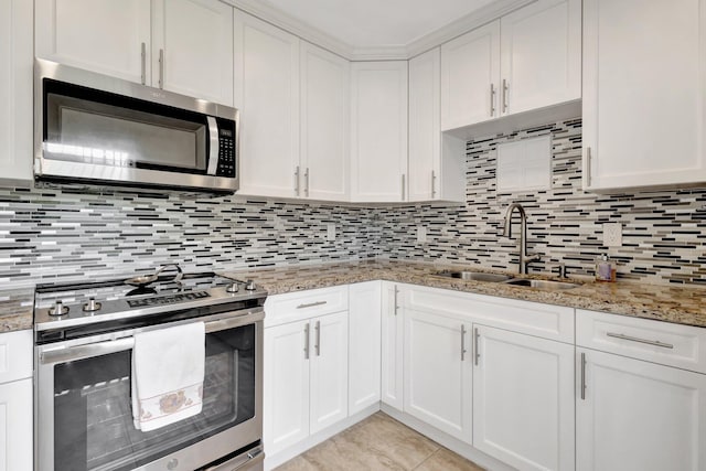 kitchen featuring white cabinets, appliances with stainless steel finishes, a sink, backsplash, and light tile patterned flooring