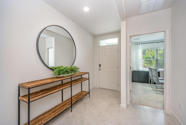 entryway featuring light colored carpet, visible vents, baseboards, and light tile patterned flooring