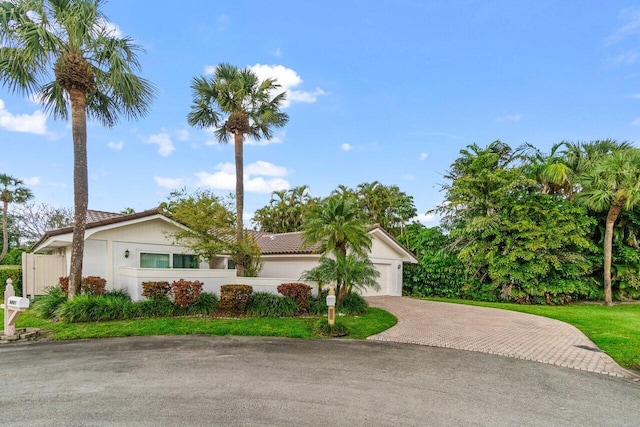 view of front of house featuring a garage, decorative driveway, a tile roof, and stucco siding