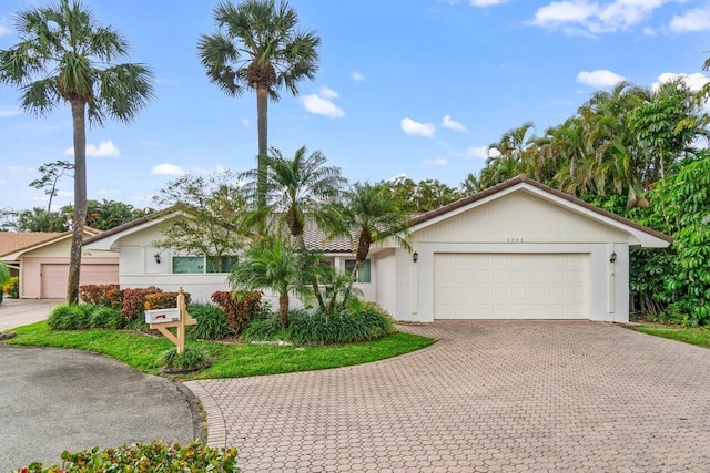 view of front facade with decorative driveway, a tiled roof, an attached garage, and stucco siding