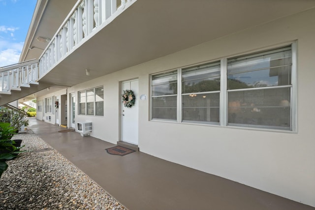 view of patio with stairway and a wall unit AC