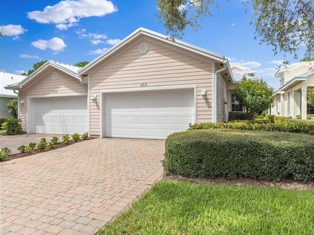 ranch-style home featuring decorative driveway and an attached garage